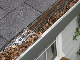 Picture of a gutter with leaves and sticks clogged up. 